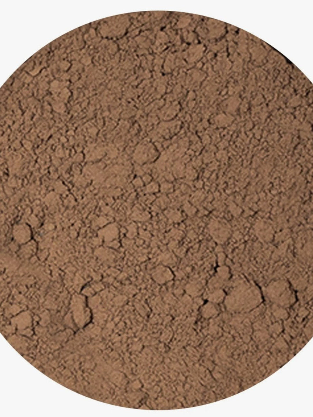 A close-up circular view of a fine brown powder or textured material filling most of the frame, with a light neutral background visible around the edges.