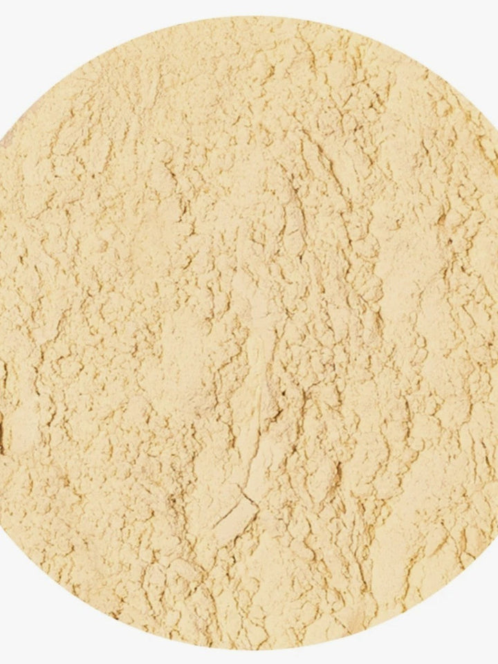 A close-up circular view of a light beige textured powder on a white background.