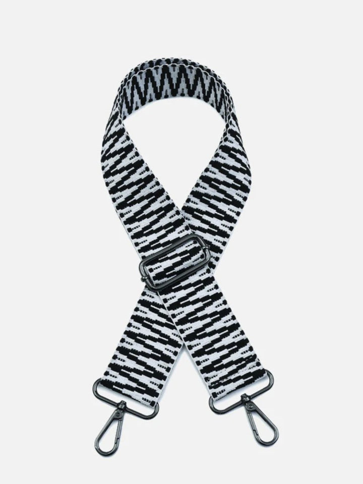 A black and white patterned fabric shoulder strap with a silver metal buckle and two silver carabiner clips, shown against a light gray background.