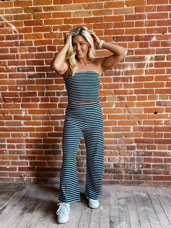 Model wearing the Boardwalk Strapless Stripe 2pc Set in navy and sky, with a brick wall background.
