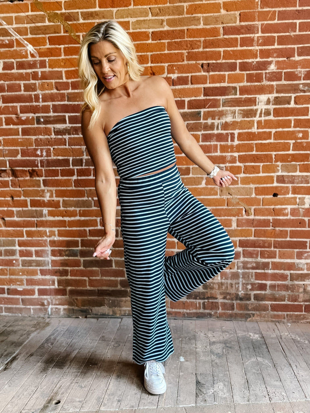Model wearing the Boardwalk Strapless Stripe 2pc Set in navy and sky, with a brick wall background.