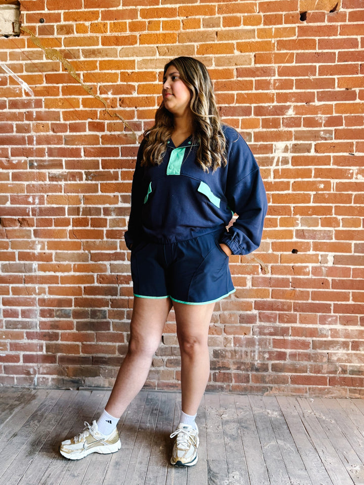 A woman wearing a navy and mint green French terry set with an oversized fit and contrast details.