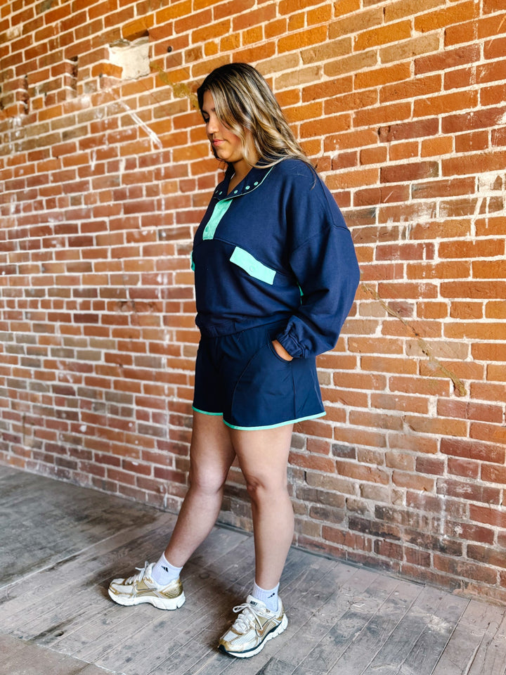 A woman wearing a navy and mint green French terry set with an oversized fit and contrast details.