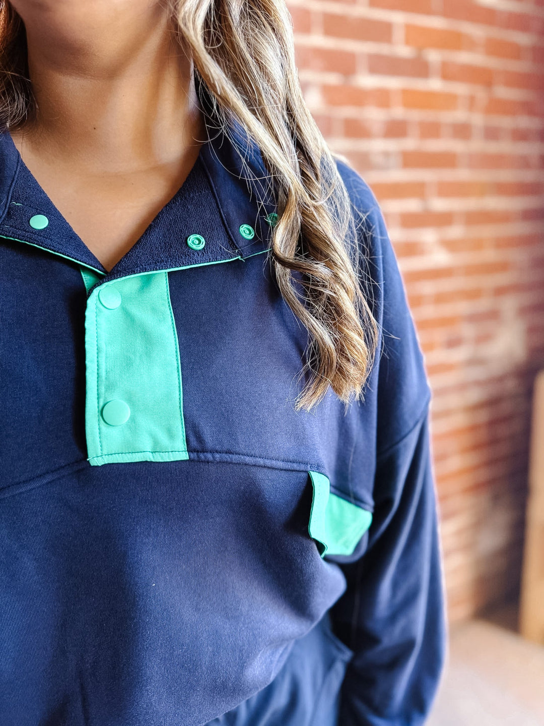 A woman wearing a navy and mint green French terry set with an oversized fit and contrast details.