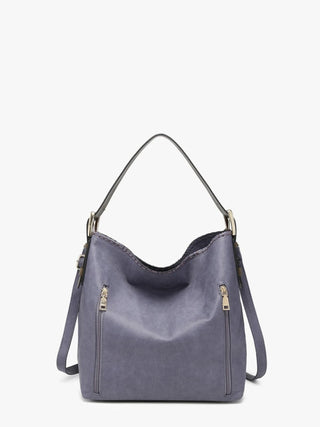 A dusty purple faux-leather hobo shoulder bag with gold-tone hardware, featuring two front zip pockets and a single shoulder strap, set against a plain white background.