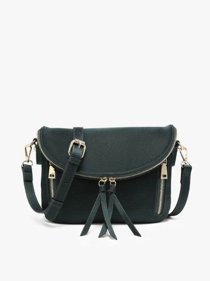A dark green faux-leather crossbody bag with gold-tone hardware, featuring a front flap with a buckle, a top zipper, side zippers, and two hanging tassels, shown against a plain white background.