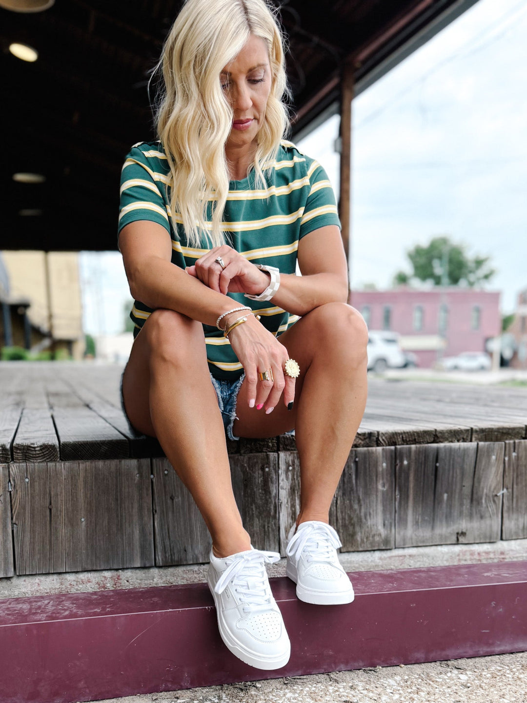 Person wearing white low top sneakers with a lace-up design and perforated toe box detail.