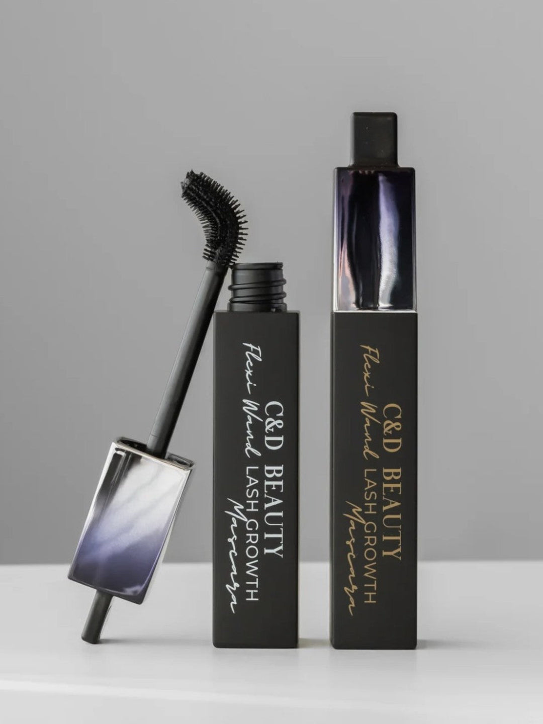 C&amp;D Beauty Fine Wire Lash Growth Serum in a black rectangular tube with gold lettering, shown alongside its applicator wand and cap on a light gray background.