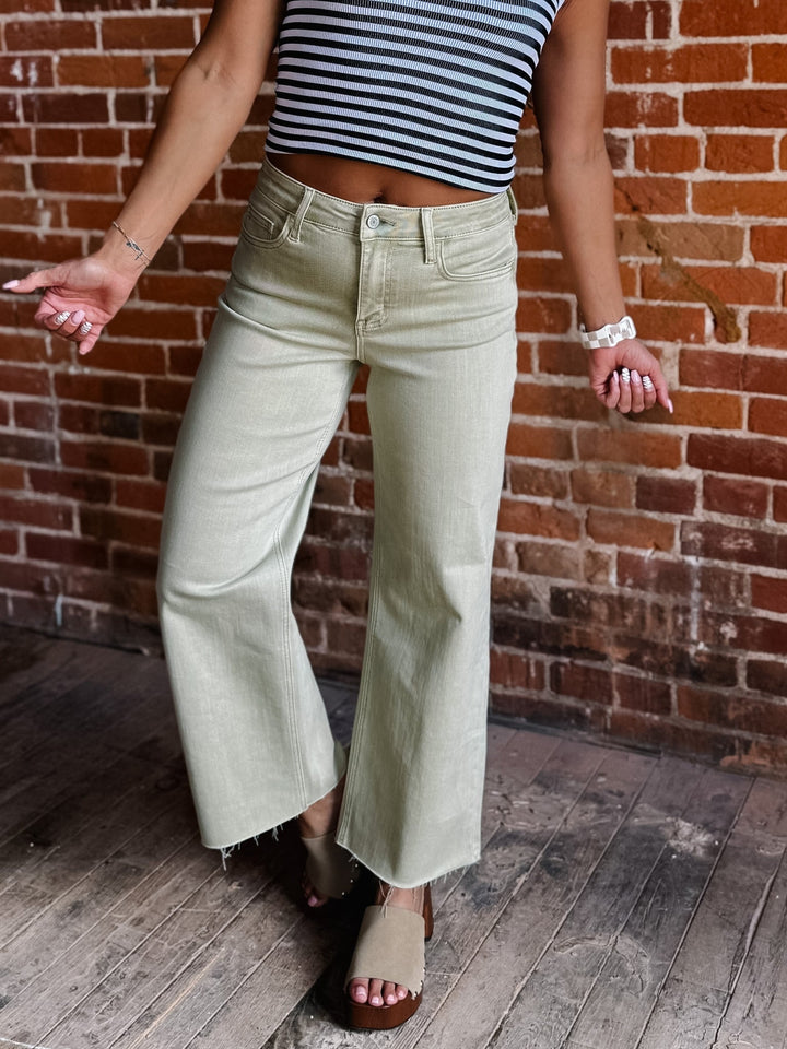 Model wearing olive wide leg crop jeans with a striped top and sandals.