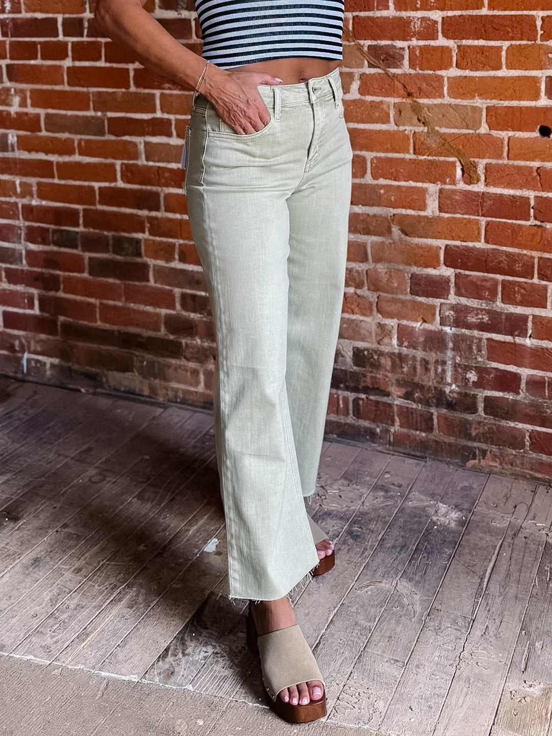 Model wearing olive wide leg crop jeans with a striped top and sandals.