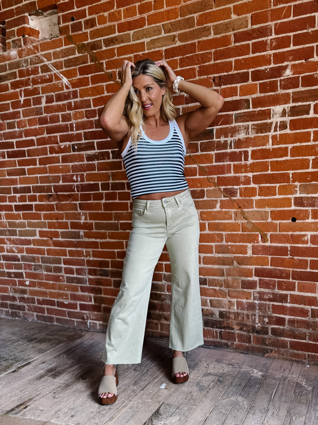 Model wearing olive wide leg crop jeans with a striped top and sandals.