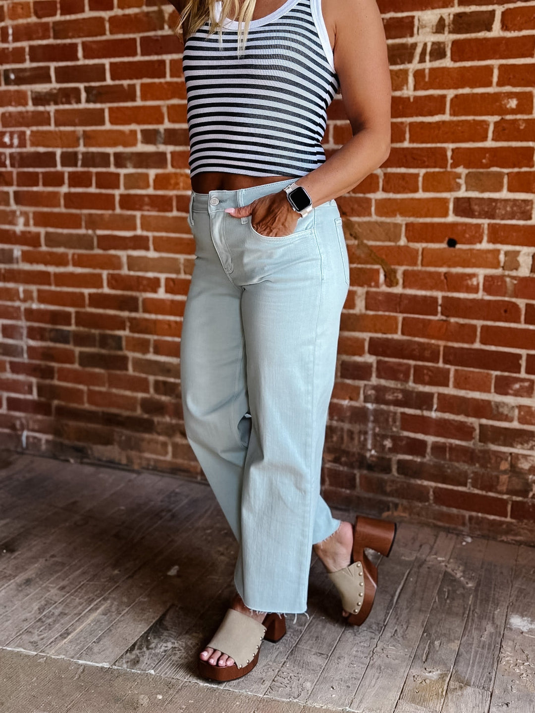 Model wearing wide leg crop jeans in Winter Sky with striped tank and sandals.