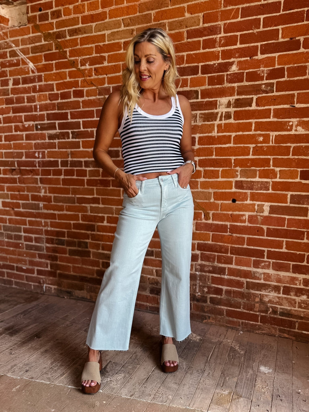 Model wearing wide leg crop jeans in Winter Sky with striped tank and sandals.
