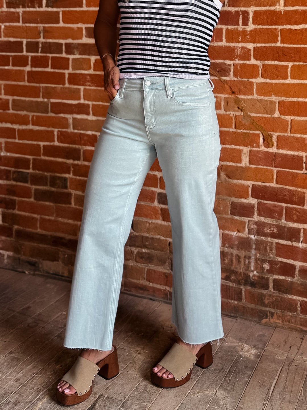 Model wearing wide leg crop jeans in Winter Sky with striped tank and sandals.