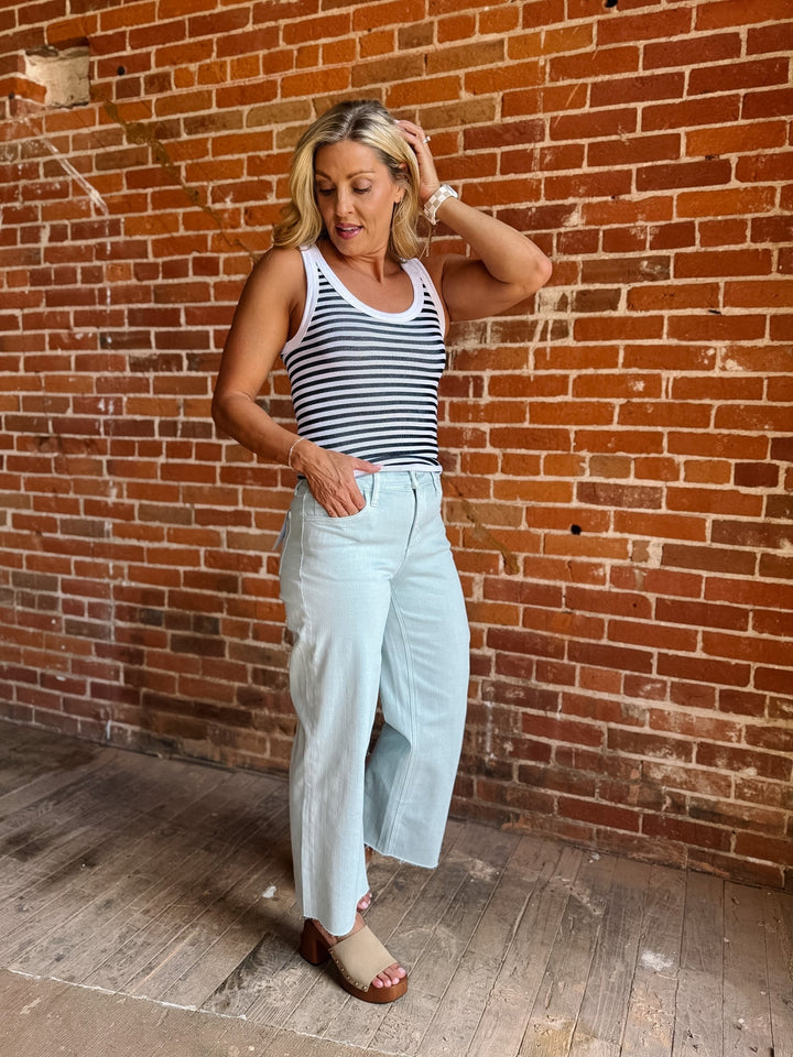 Model wearing wide leg crop jeans in Winter Sky with striped tank and sandals.