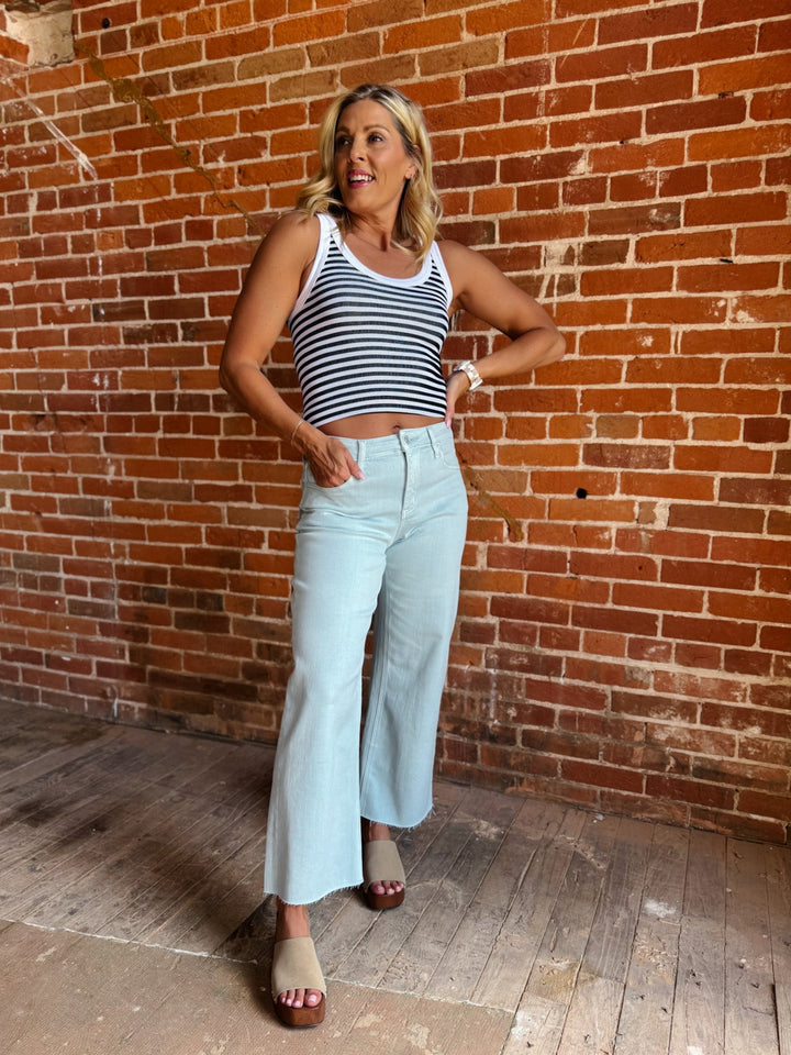 Model wearing wide leg crop jeans in Winter Sky with striped tank and sandals.
