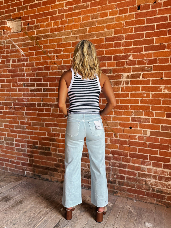 Model wearing wide leg crop jeans in Winter Sky with striped tank and sandals.