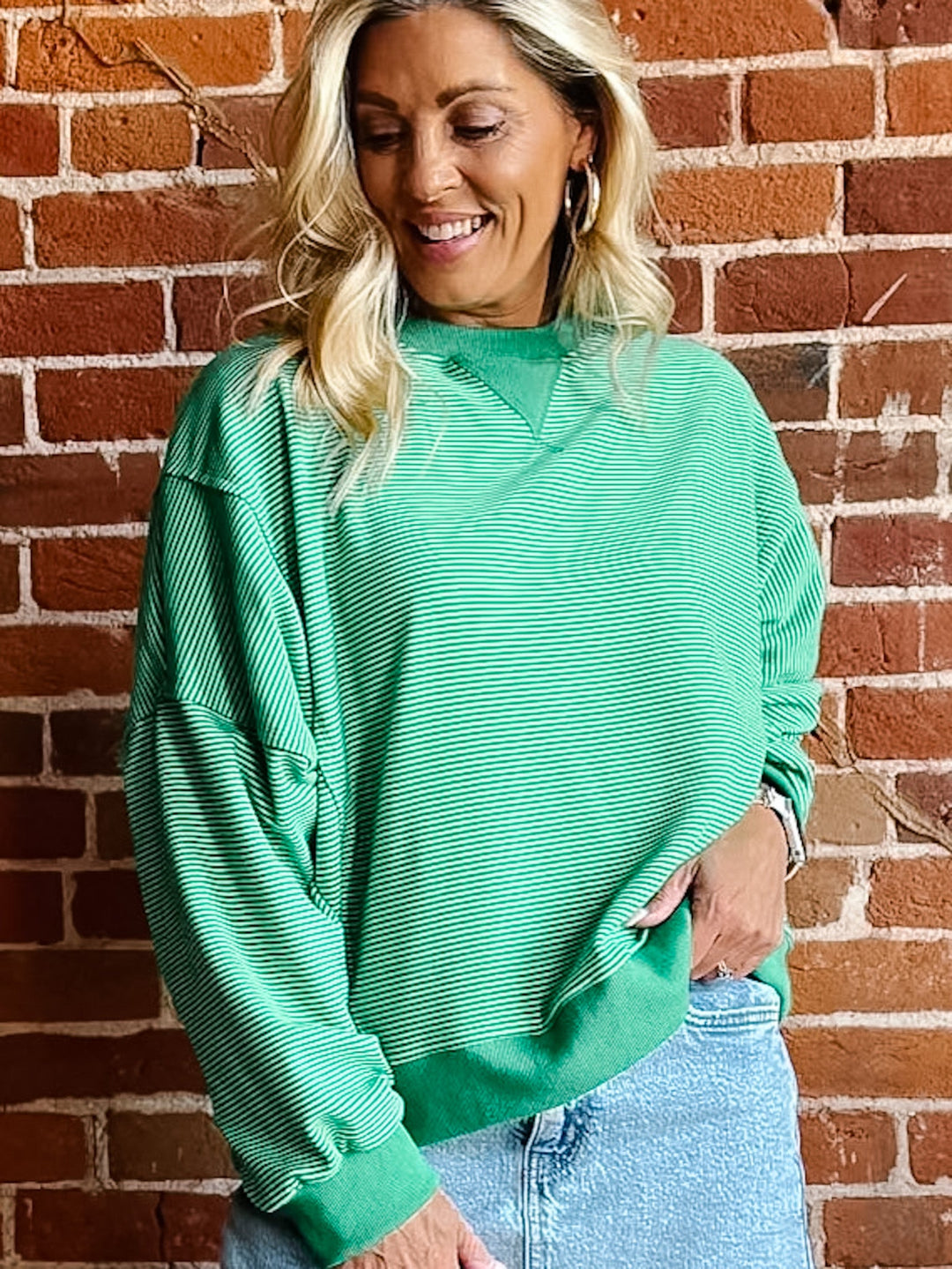 Lime green striped sweatshirt with relaxed fit and ribbed cuffs worn by a smiling woman.
