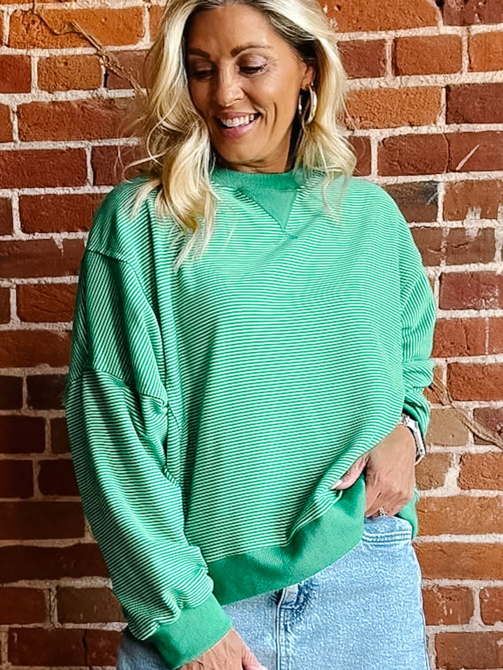 Lime green striped sweatshirt with relaxed fit and ribbed cuffs worn by a smiling woman.