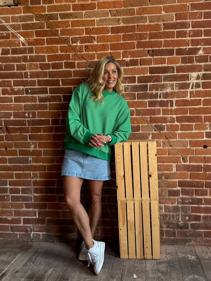 Lime green striped sweatshirt with relaxed fit and ribbed cuffs worn by a smiling woman.