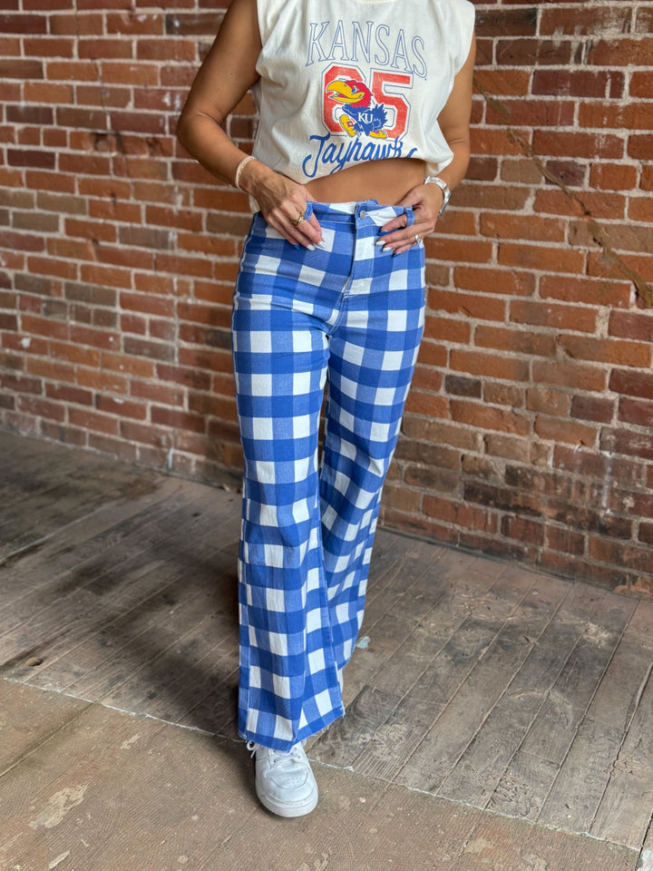 A person wearing blue and white gingham wide-leg pants, a cream sleeveless crop top with a colorful &