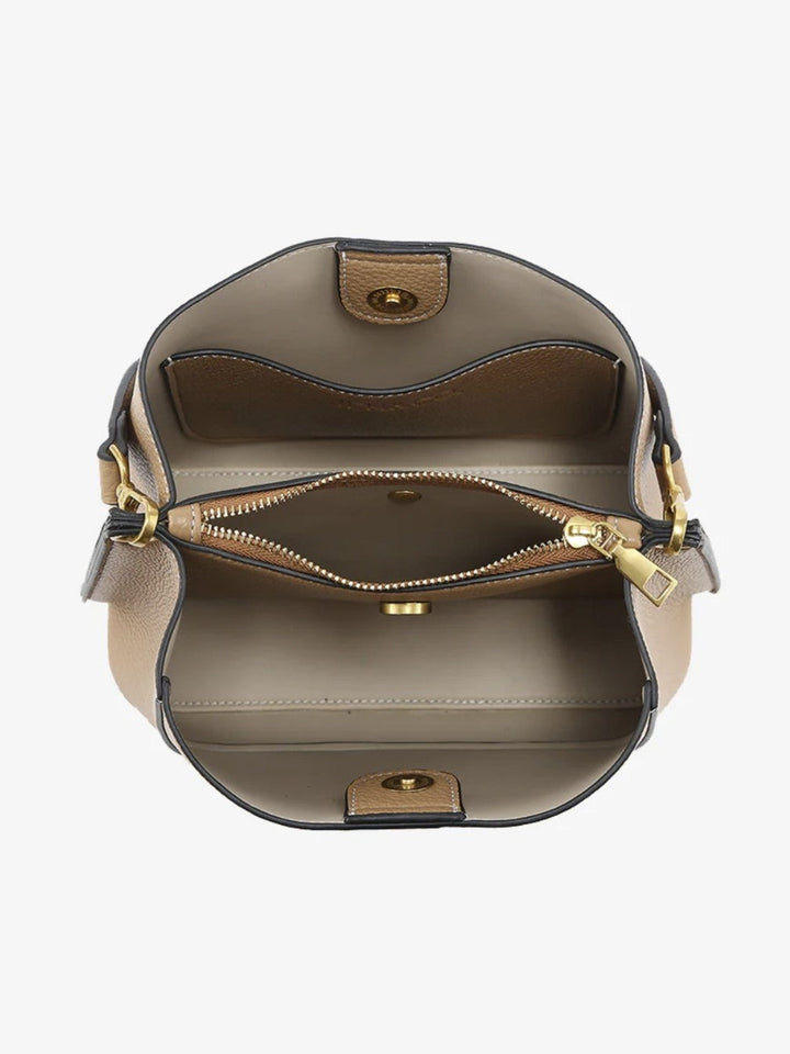 Top-down view of a structured handbag showing its interior, featuring a taupe leather exterior, a beige interior lining, a zippered compartment, and gold-tone hardware.