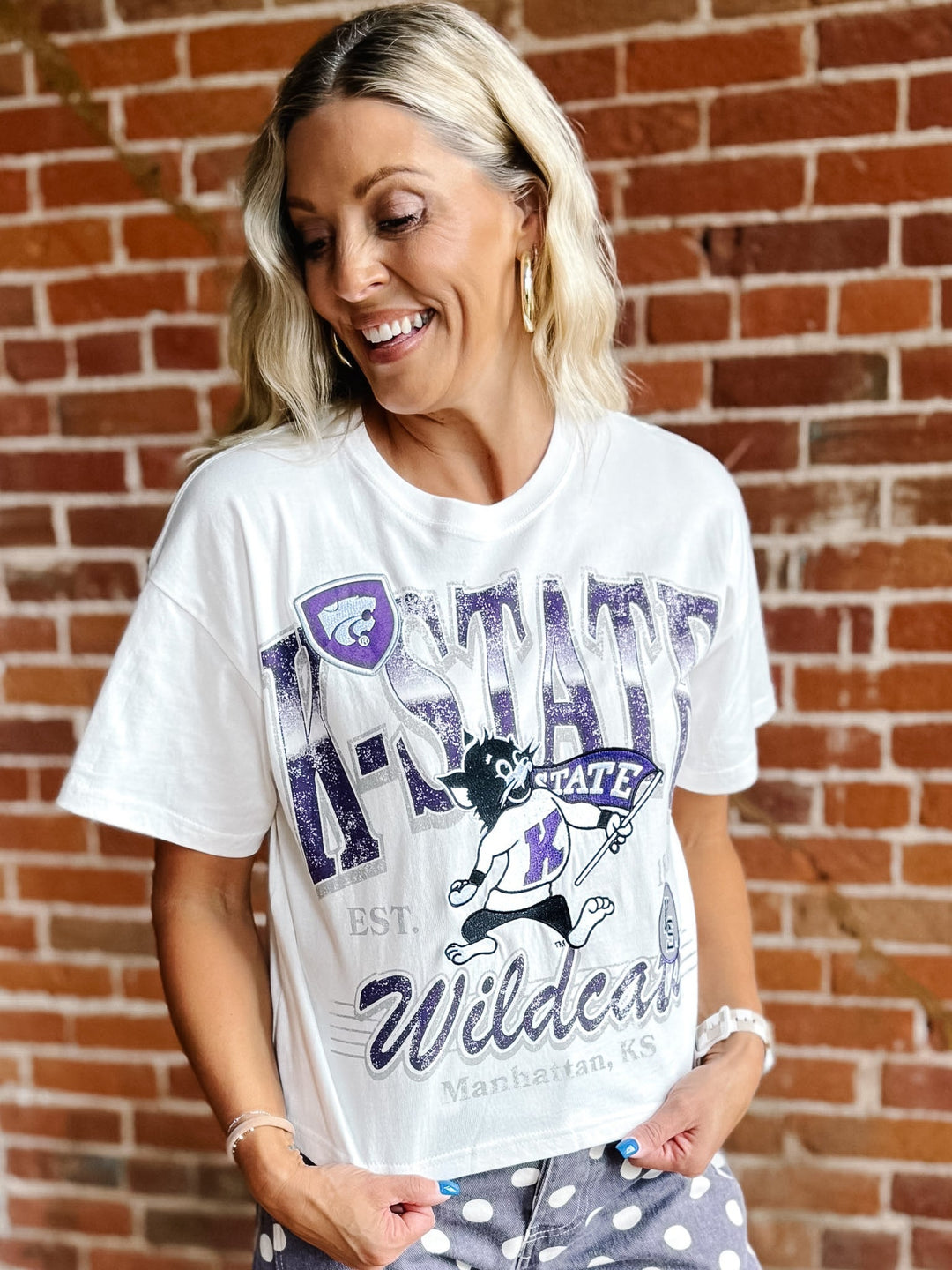 A woman wearing a white graphic t-shirt with purple and black &