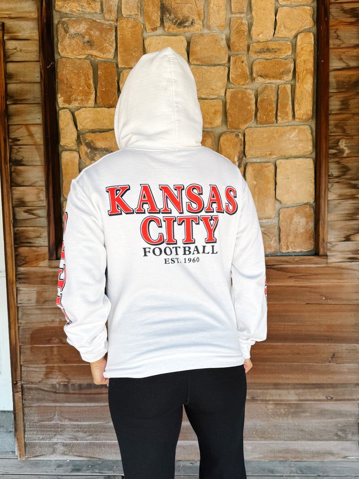 A person viewed from behind wearing a white hooded sweatshirt with a large red and black &