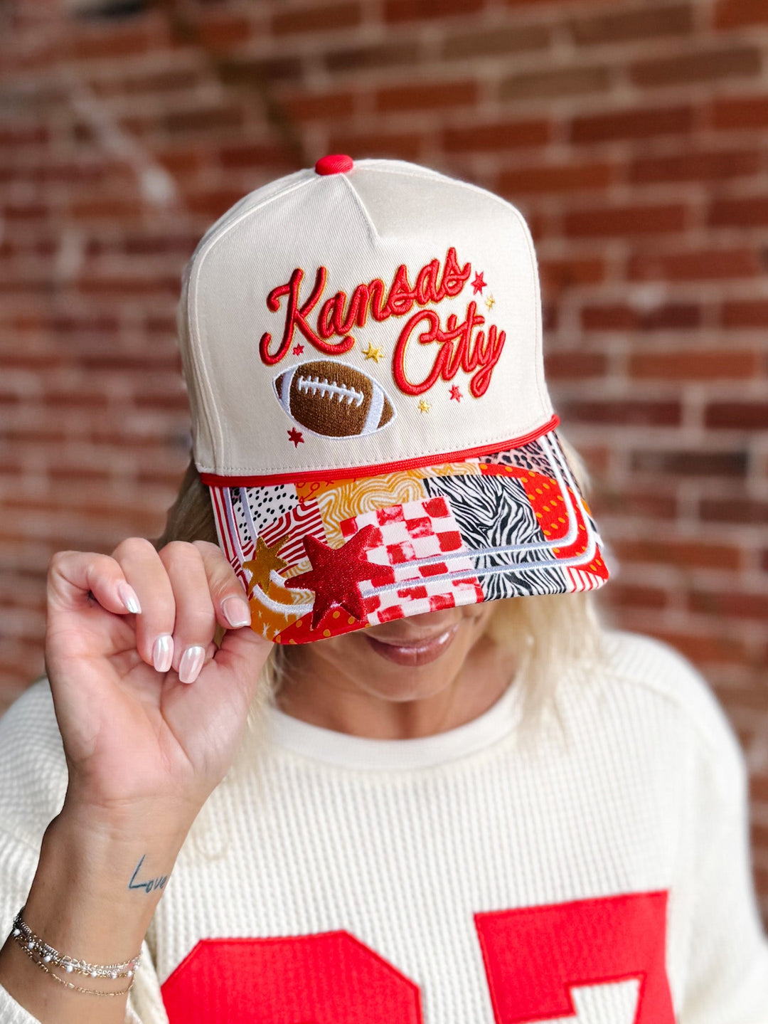 A person wearing a cream snapback cap with &