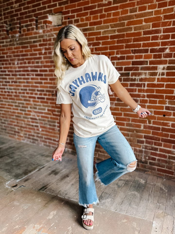 A woman posing in a white graphic t-shirt with a blue &