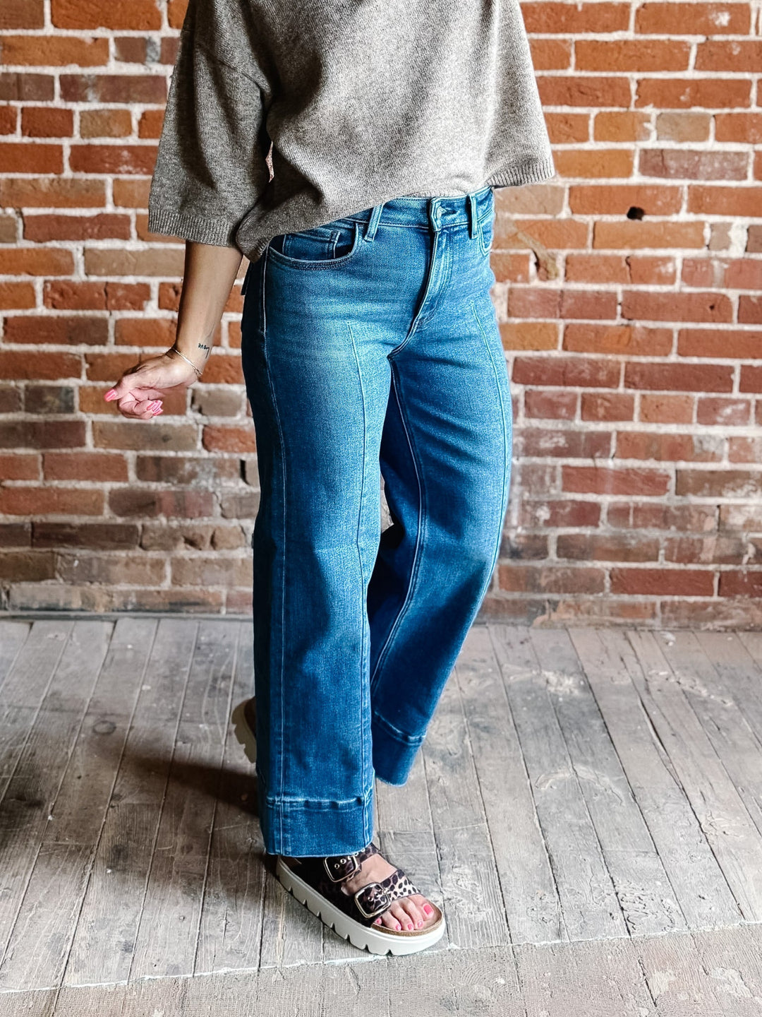 Wide leg jeans in medium dark wash with pintuck front detail and high-rise fit.