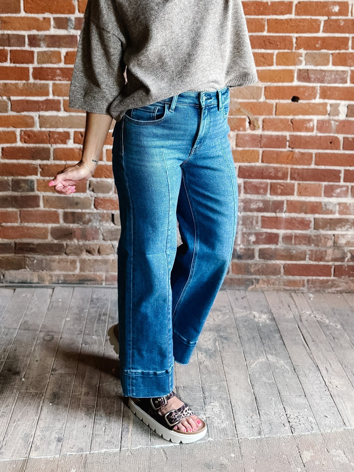 Wide leg jeans in medium dark wash with pintuck front detail and high-rise fit.