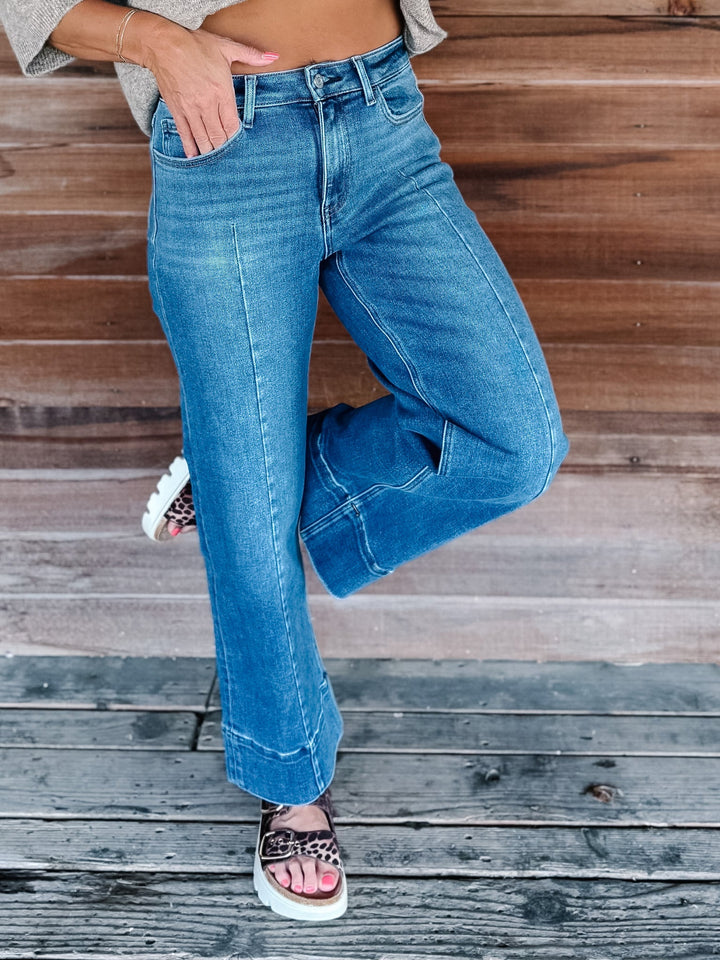 Wide leg jeans in medium dark wash with pintuck front detail and high-rise fit.