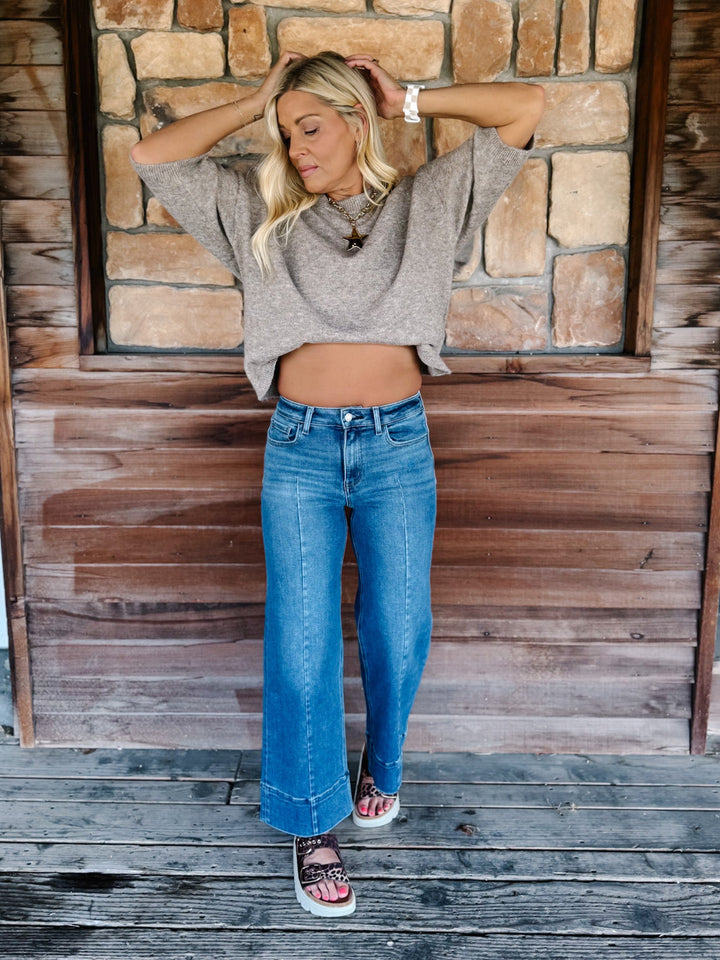 Wide leg jeans in medium dark wash with pintuck front detail and high-rise fit.