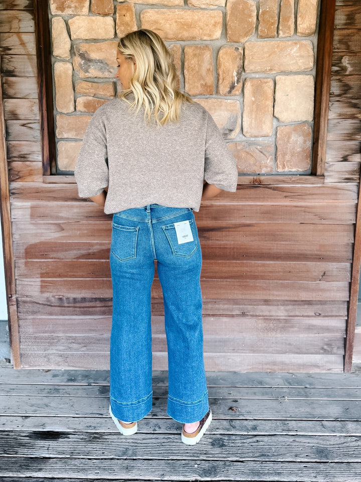 Wide leg jeans in medium dark wash with pintuck front detail and high-rise fit.