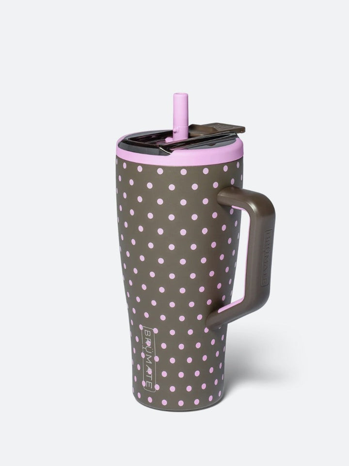A tall insulated travel tumbler with a handle, featuring a dark gray body with a light pink polka dot pattern, a matching pink lid, and a pink straw, shown on a light gray background.