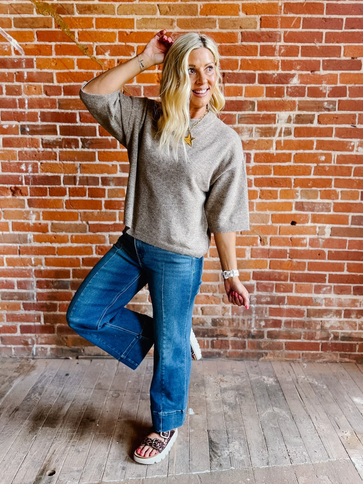Woman wearing an oatmeal heathered half sleeve sweater with a relaxed fit and crew neckline.