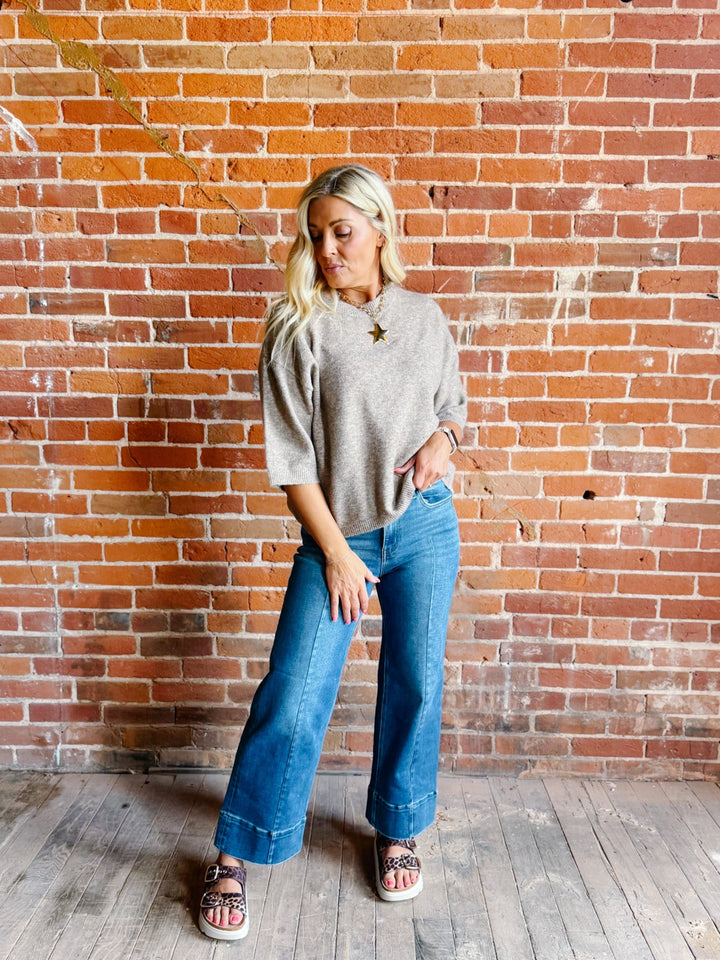 Woman wearing an oatmeal heathered half sleeve sweater with a relaxed fit and crew neckline.