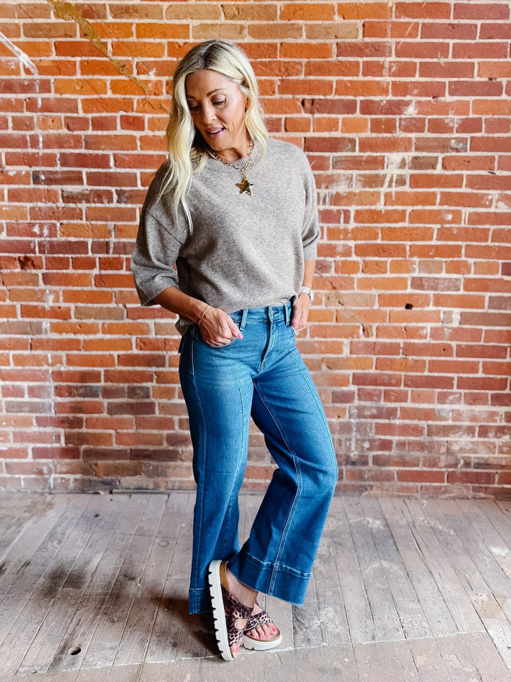 Woman wearing an oatmeal heathered half sleeve sweater with a relaxed fit and crew neckline.