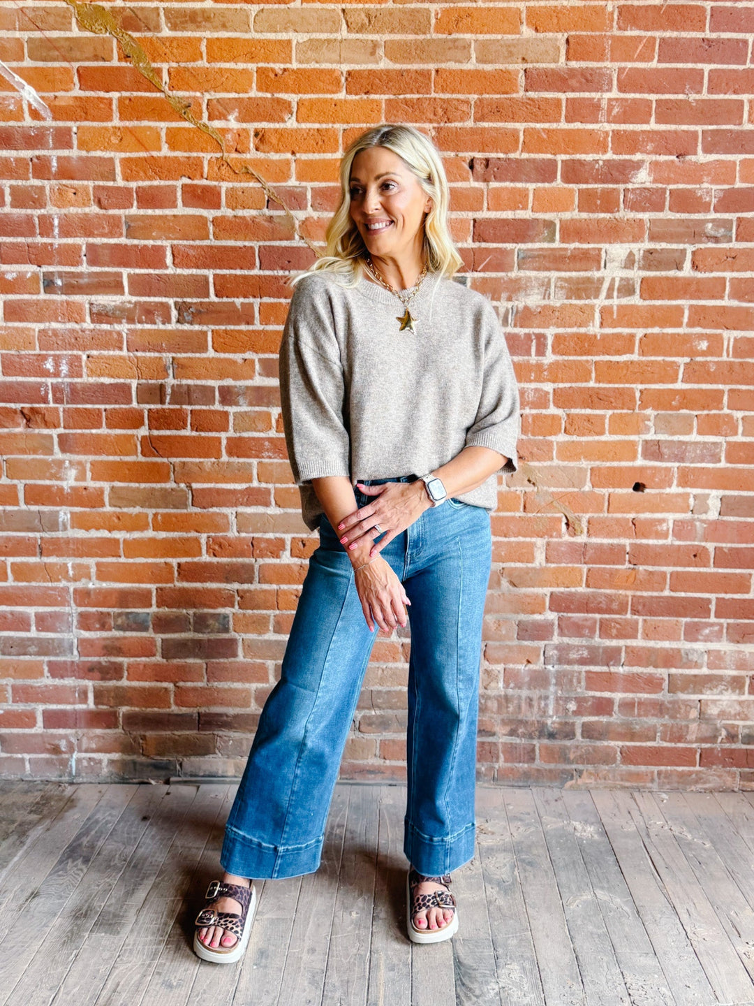 Woman wearing an oatmeal heathered half sleeve sweater with a relaxed fit and crew neckline.