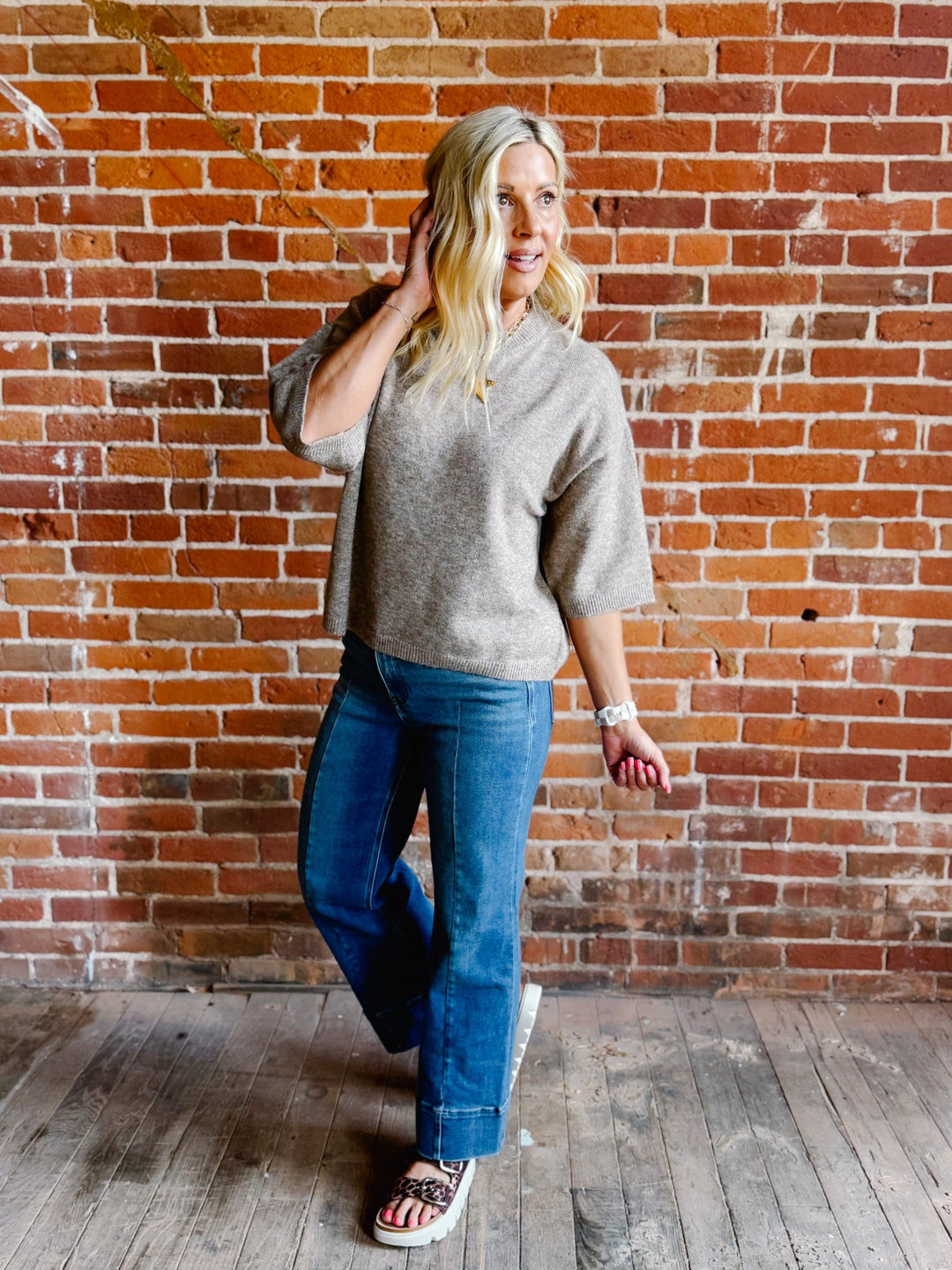 Woman wearing an oatmeal heathered half sleeve sweater with a relaxed fit and crew neckline.