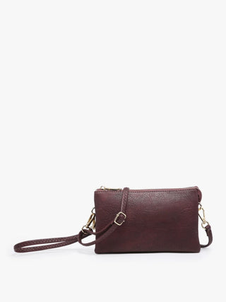 A small rectangular crossbody bag in textured plum faux leather with gold-tone hardware, featuring a matching wristlet strap and a zip-top closure, shown against a plain white background.