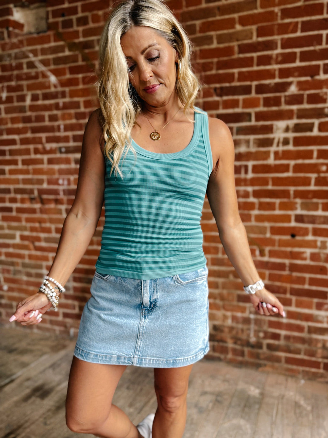 Woman wearing the Flip Side Stripe Tank in Dusty Teal with a denim skirt against a brick wall.