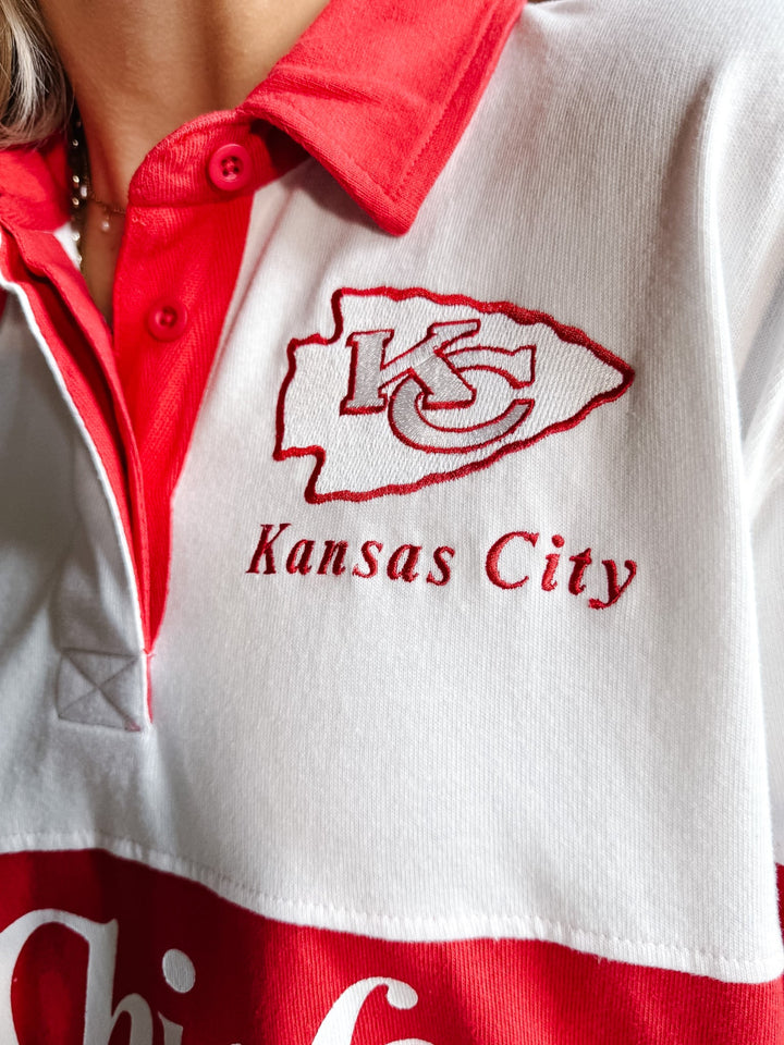 Close-up of a white and red polo shirt featuring an embroidered Kansas City Chiefs logo and text on the chest.