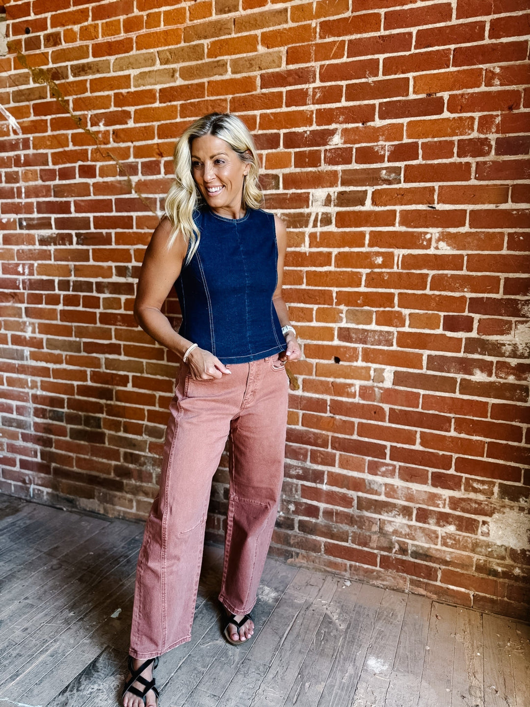Woman wearing sleeveless dark denim top with open back and tie detail