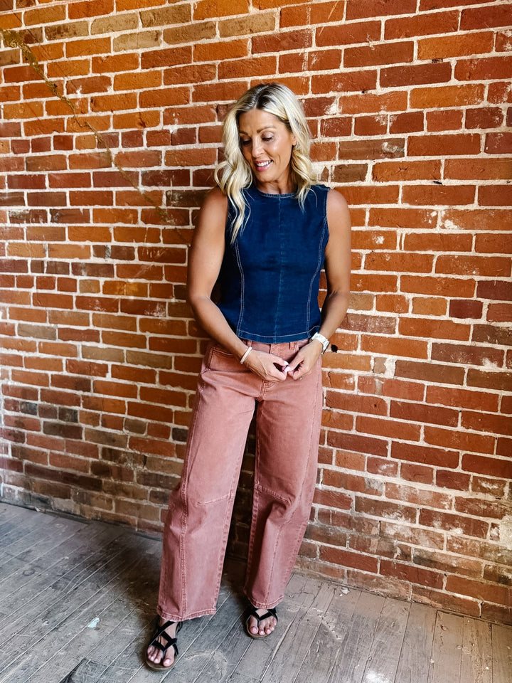 Woman wearing sleeveless dark denim top with open back and tie detail