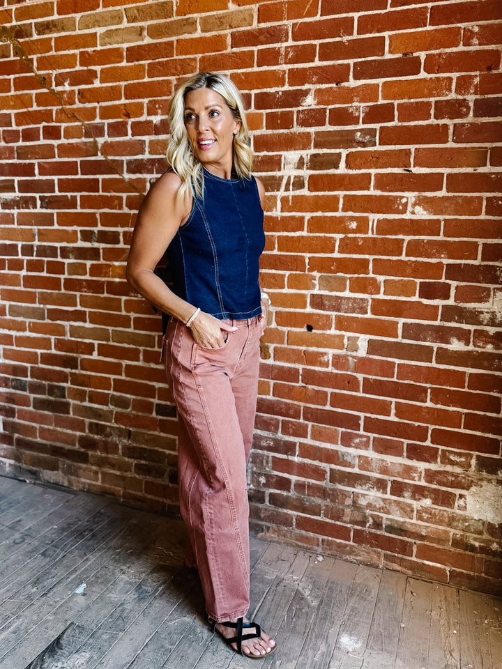 Woman wearing sleeveless dark denim top with open back and tie detail