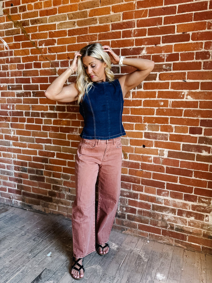 Woman wearing sleeveless dark denim top with open back and tie detail