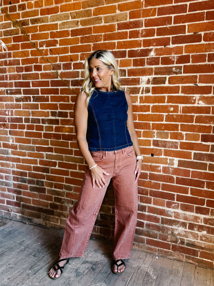 Woman wearing sleeveless dark denim top with open back and tie detail
