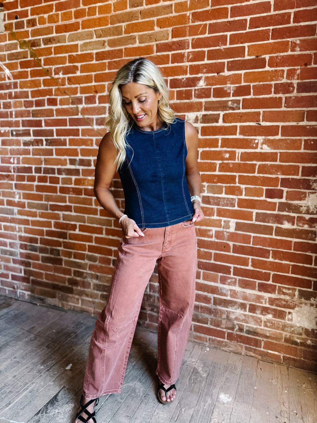 Woman wearing sleeveless dark denim top with open back and tie detail